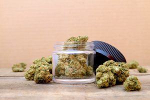 Marijuana in Open Jar Surrounded by Cannabis Buds